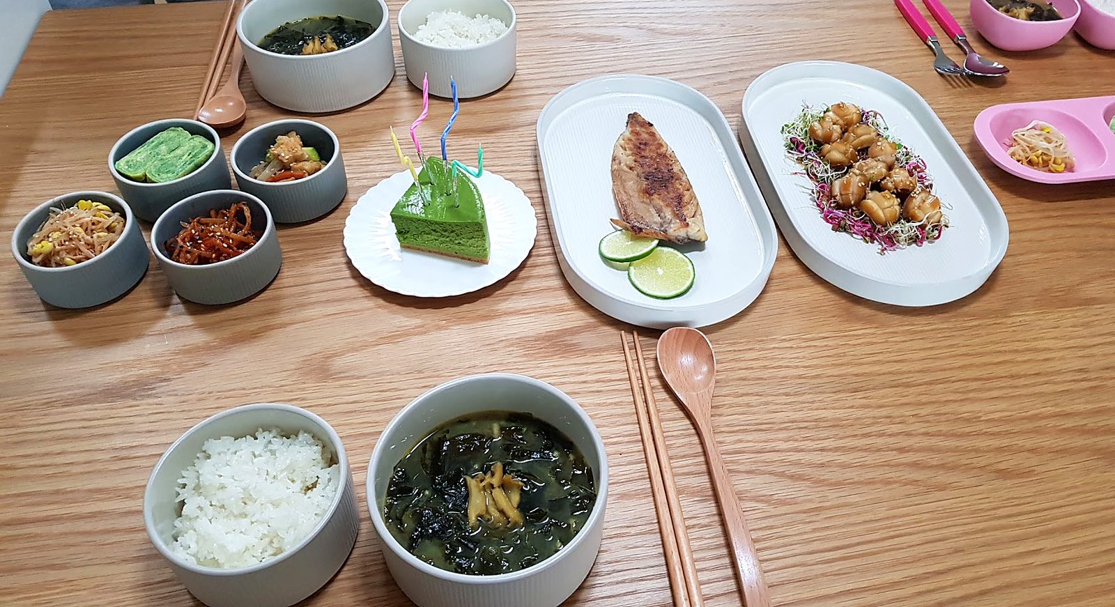 Homemade Korean birthday breakfast with clam miyeokguk, rice, six side dishes, a grilled fish and a green tea cake