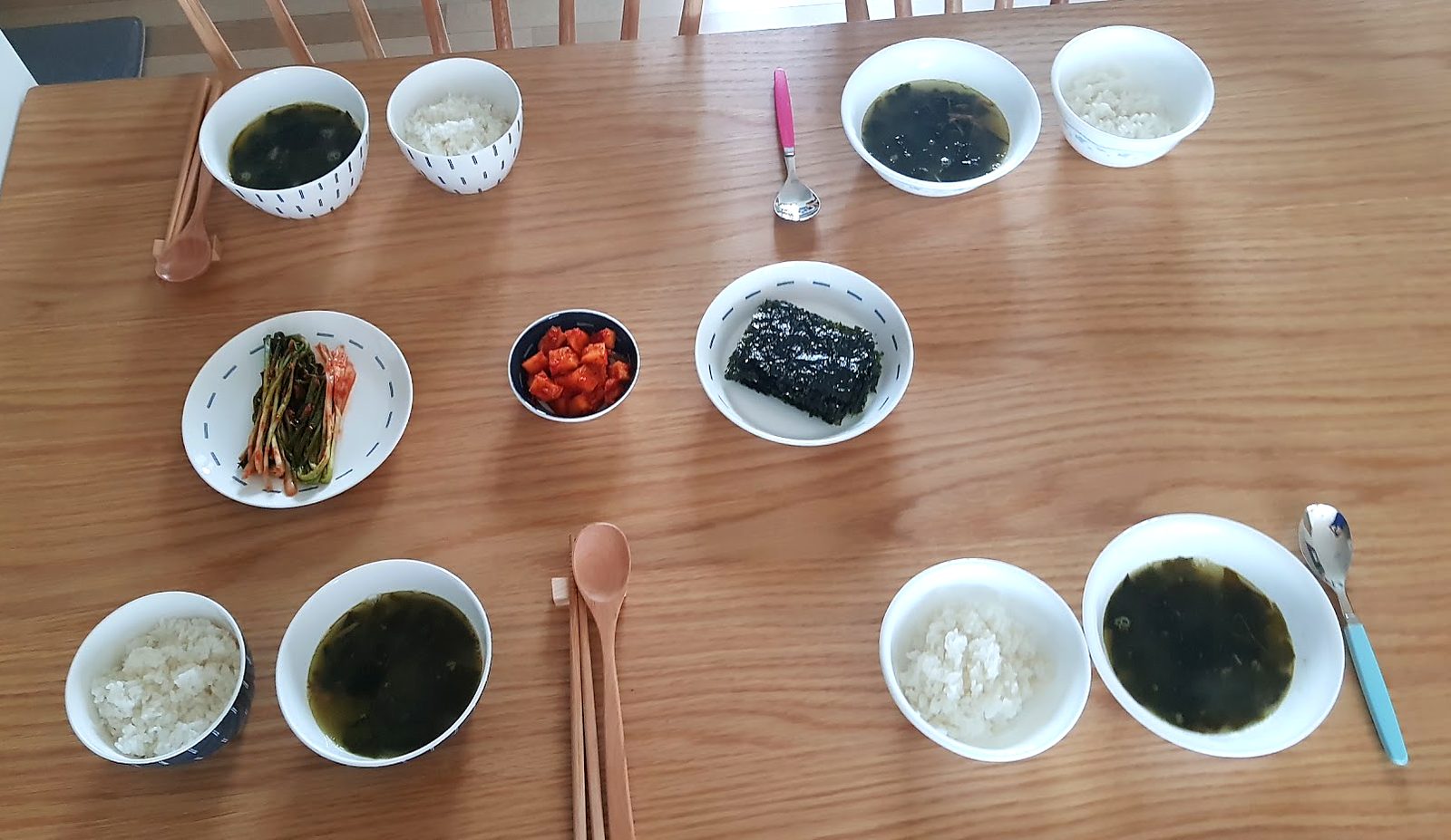 Korean home breakfast table set for four with miyeokguk seaweed soup, white rice, pa-kimchi, kkakdugi and roasted gim