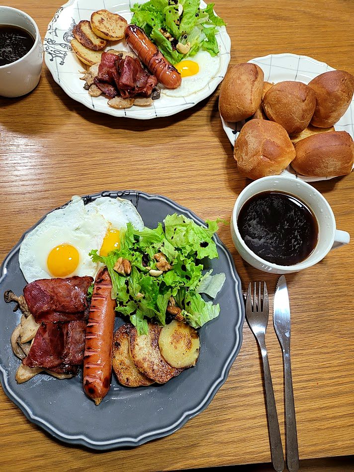 Weekend brunch for two at a Seoul home: fried eggs, bacon, sausage, pan-fried potatoes, salad, rolls and black coffee